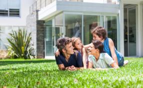 Image of nuclear family lying on green front lawn smiling