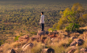 This is an image of man standing on a rock in the Far West