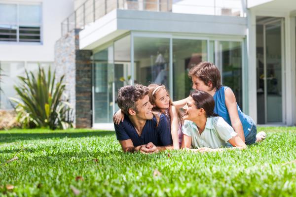 Image of nuclear family lying on green front lawn smiling