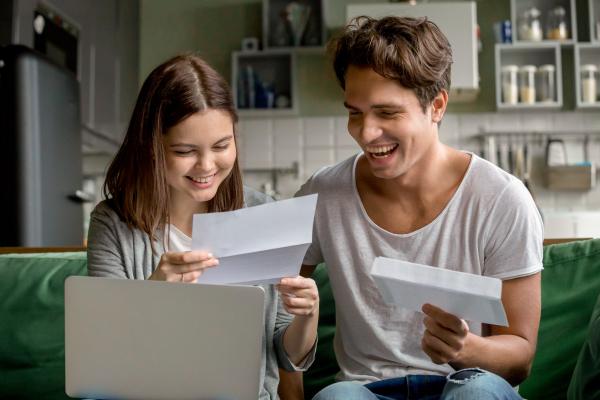 Image of a young hetero couple sitting at table reading paperwork together