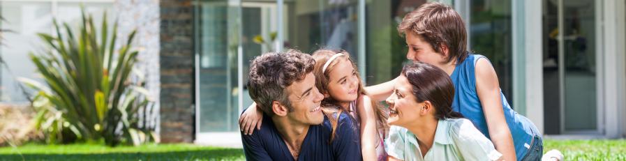 Image of nuclear family lying on green front lawn smiling