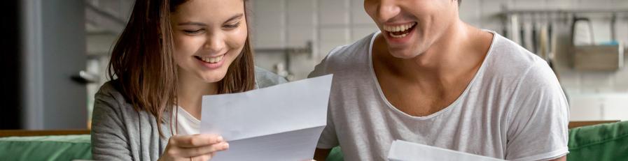 Image of a young hetero couple sitting at table reading paperwork together