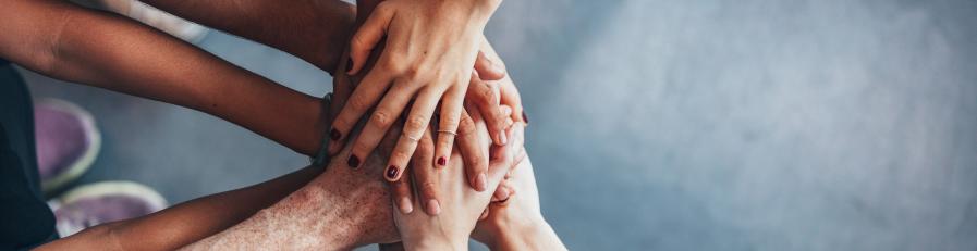 Image of seven people's hands upon one another