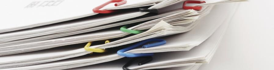 Close up image of documents in piles and held together with alternate coloured paper clips