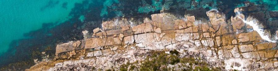 Aerial image of a shore line and waves breaking against sandstone