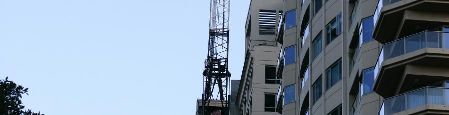 This is an image of a crane near some high rise buildings